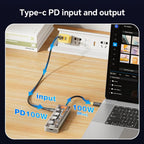 USB-C PD 100W charging adapter connected to a power strip and laptop on a wooden desk.